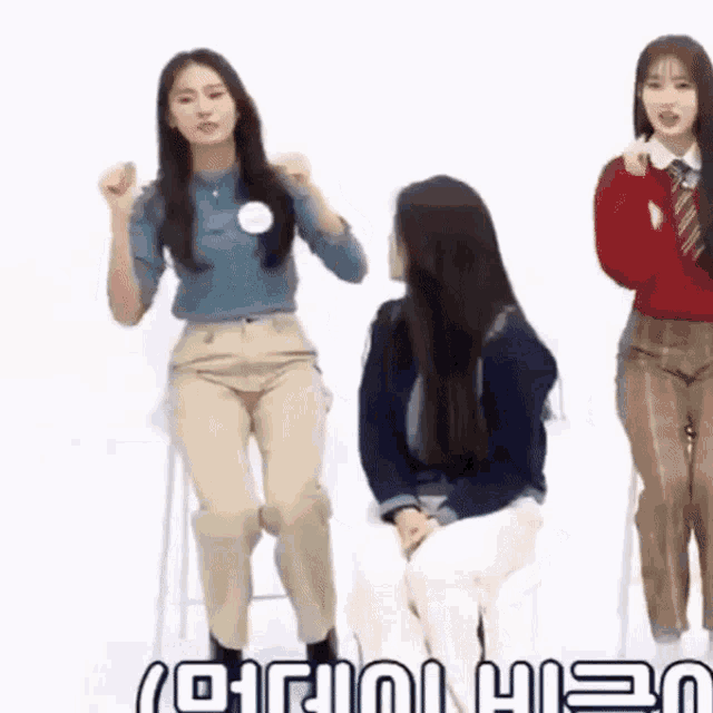 a group of girls are standing and sitting in front of a sign that says ' uei ' on it