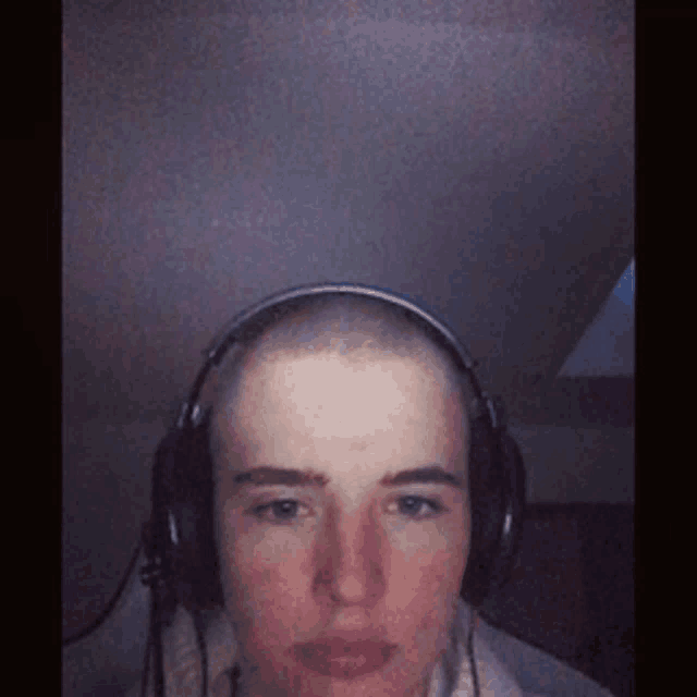 a man with a shaved head wearing headphones looks at the camera