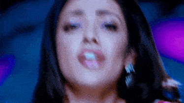 a close up of a woman 's face with a blue background and purple lights behind her .