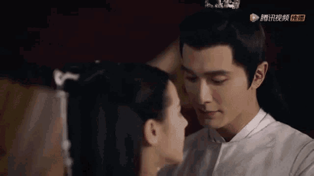 a man and a woman are looking into each other 's eyes . the man is wearing a crown on his head .
