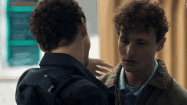 two young men are looking at each other and hugging each other .