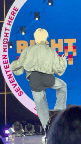 a person standing on a stage with a sign that says seventeen right here