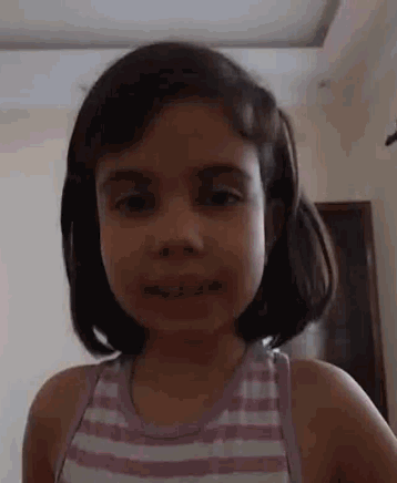 a little girl is making a funny face while wearing a pink and white striped shirt .
