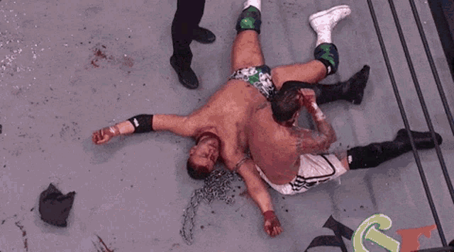 a wrestler with blood on his face is chained to another wrestler in a wrestling ring