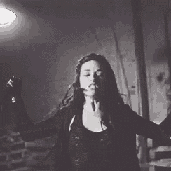 a woman in a black and white photo is dancing in a dark room .