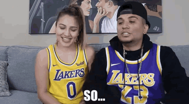 a man and a woman are sitting on a couch and the man is wearing a lakers jersey