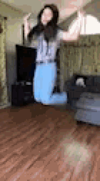 a woman is jumping in the air in a living room while holding a microphone .