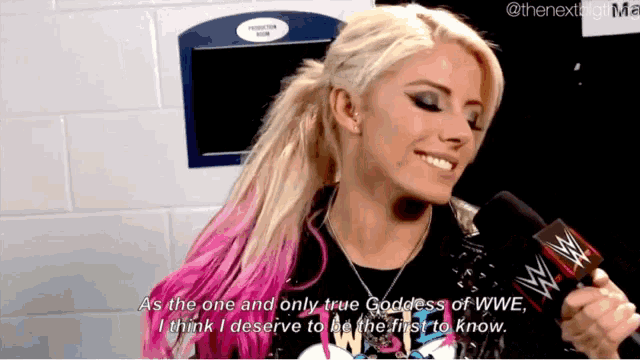 a woman with pink hair is holding a microphone and talking about being the goddess of wwe