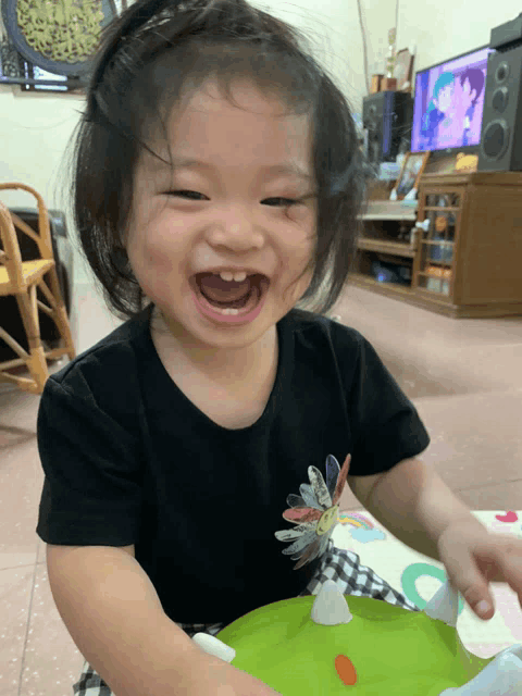 a little girl with a flower on her shirt is smiling