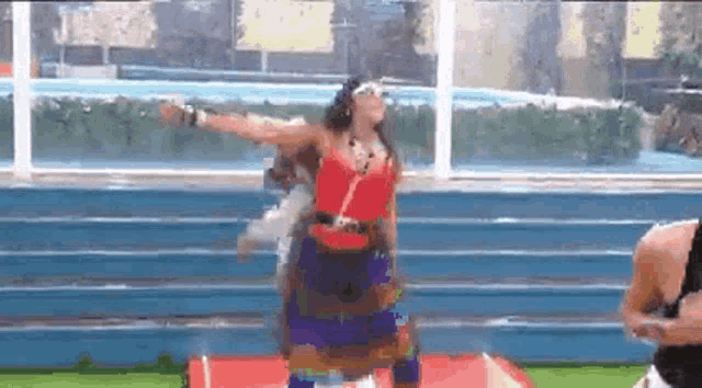a woman in a red top and a blue skirt is dancing on a red carpet .