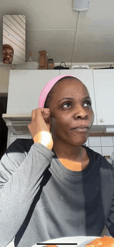 a woman wearing a pink headband is sitting in front of a mirror