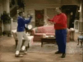 two men are dancing in a living room in front of a couch .