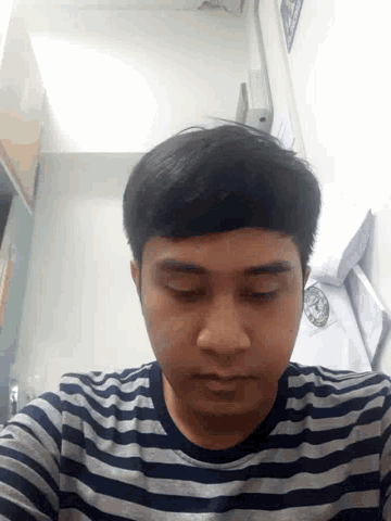 a man wearing a striped shirt looks down at something