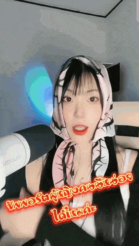 a woman wearing a scarf around her head is standing in front of a microphone that says uoquo on it