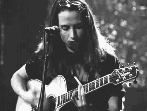 a woman is singing into a microphone while playing a guitar