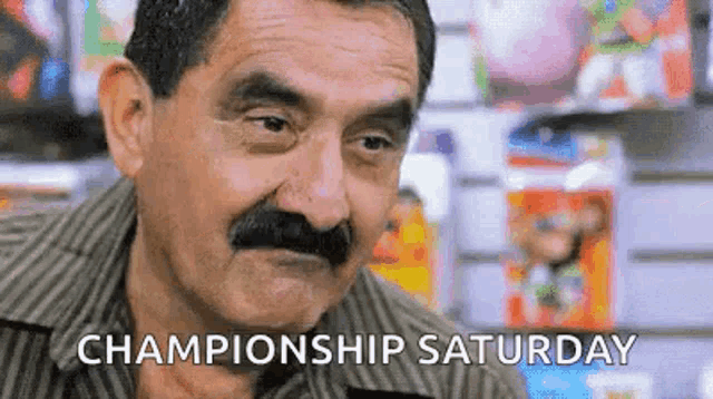 a man with a mustache and the words `` championship saturday '' written on the bottom of his face .