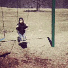 a child is playing on a swing set in a park