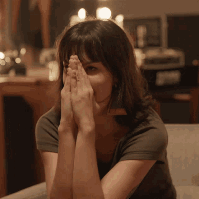 a woman covering her face with her hands while sitting down