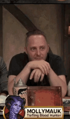 a man is sitting at a table with a sign that says mollymauk