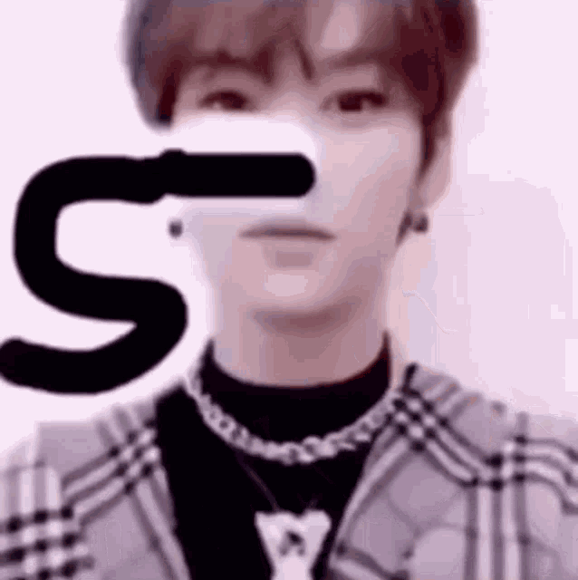a close up of a person 's face with a letter s behind it .
