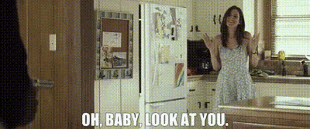 a woman in a kitchen with the words oh baby look at you