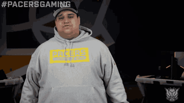 a man wearing a pacers sweatshirt is standing in front of a computer
