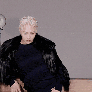 a man wearing a black fur coat and a black sweater is dancing