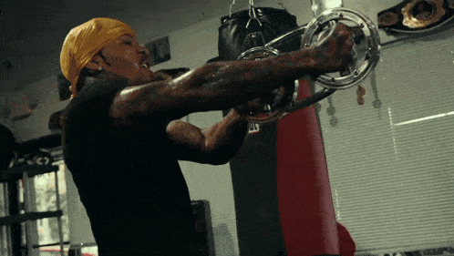 a man wearing a yellow bandana is using a machine