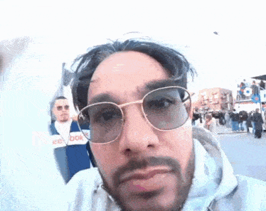 a man with a beard wearing glasses and a reebok jacket