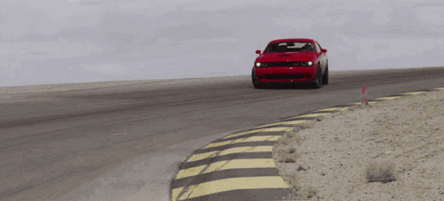 a red dodge challenger is driving on a track