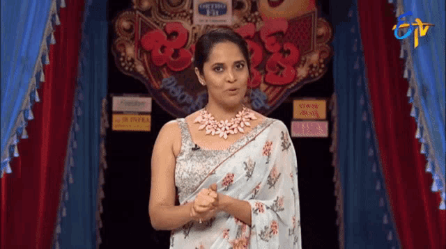 a woman in a white saree is standing in front of a sign that says ' a ' on it