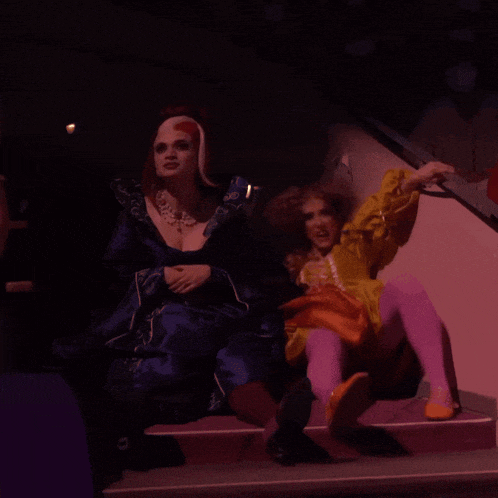 a woman in a yellow and orange dress sits on a staircase