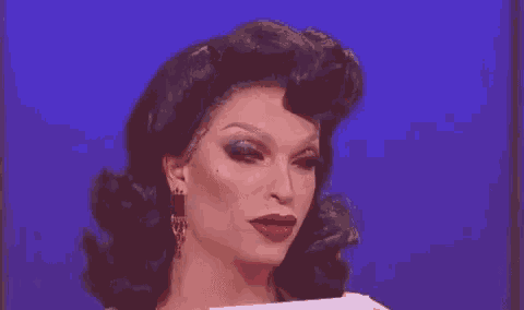 a close up of a drag queen 's face with red lipstick and earrings .