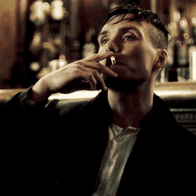 a man in a suit is smoking a cigarette