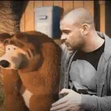a man is standing next to a stuffed bear and talking to it .