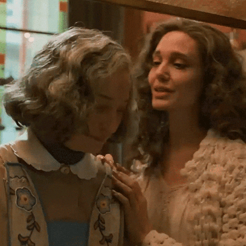 two women are standing next to each other and one of them is holding another woman 's hand .