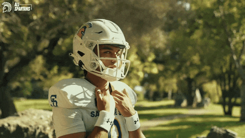 a spartans football player adjusts his helmet
