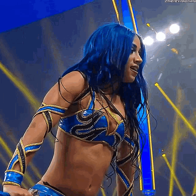 a woman with blue hair and a blue and gold outfit is standing in front of a stage .