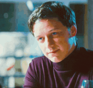 a man wearing a purple turtleneck is looking at something