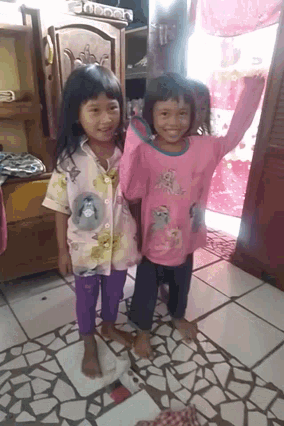 two little girls standing next to each other wearing pink shirts with cats on them