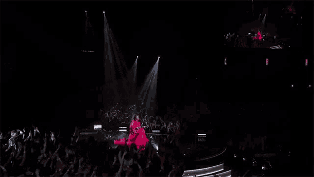 a woman in a red dress is standing on a stage in front of a crowd .