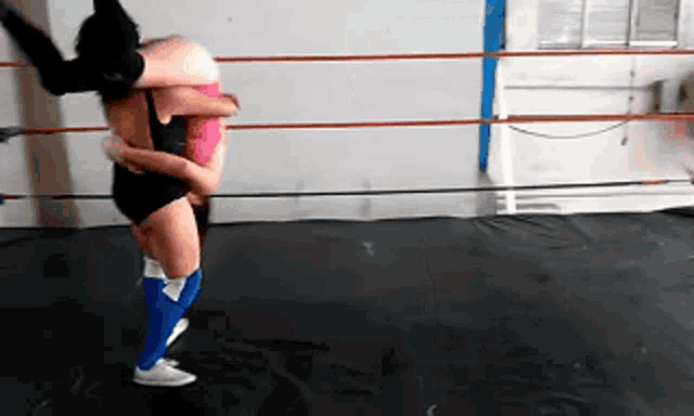 two women are wrestling in a ring and one of them is carrying the other on her back .