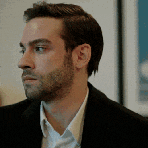 a man with a beard is wearing a black suit and white shirt