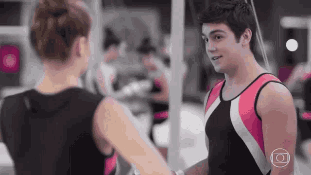 a man and a woman are standing next to each other in a gym