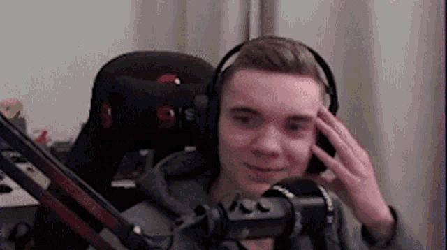 a young man wearing headphones is sitting in front of a microphone in a room .