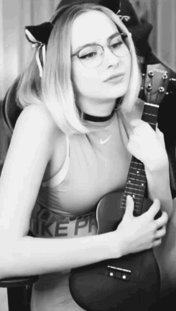 a black and white photo of a woman holding a guitar with the word nike on her shirt