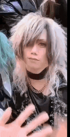 a close up of a person 's face with long white hair and a choker around their neck .