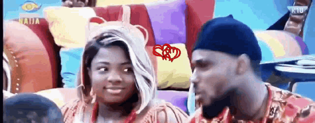 a man and a woman are sitting next to each other on a colorful couch with the word naija on the screen