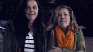 two women are standing next to each other with their arms crossed .