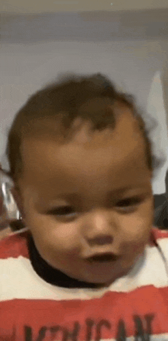 a baby is wearing a red and white striped shirt .